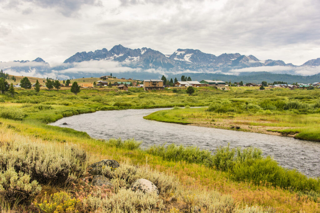 cabins in front of mountain range with river alongside