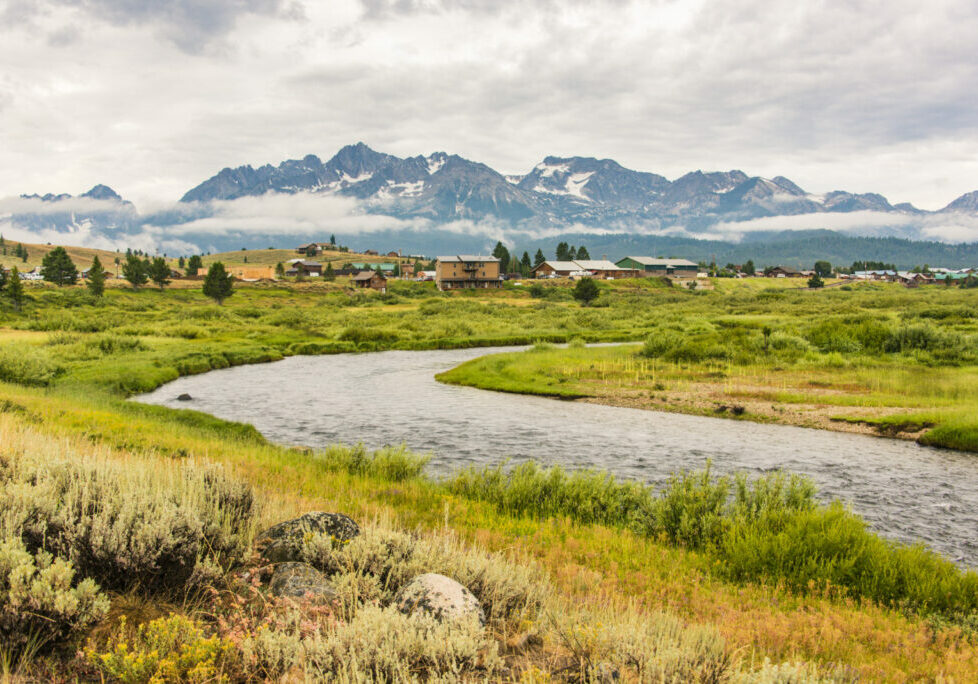 cabins in front of mountain range with river alongside